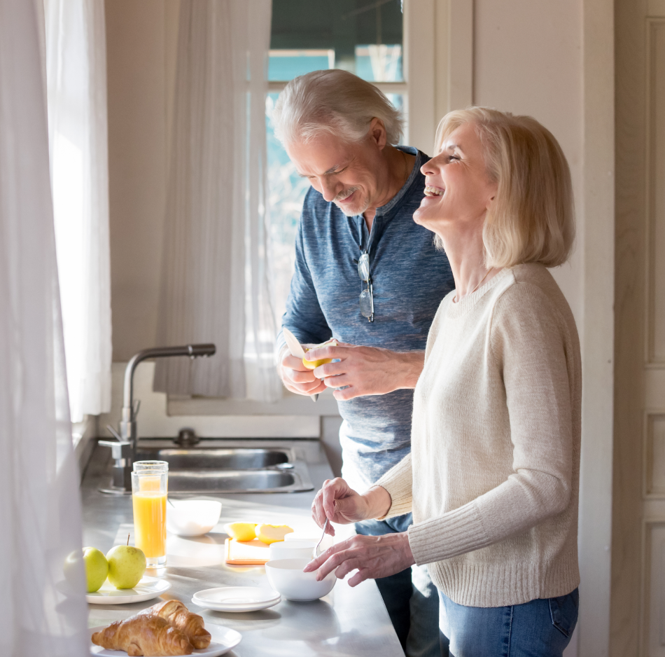 Couple laughing in kitchen with breakfast